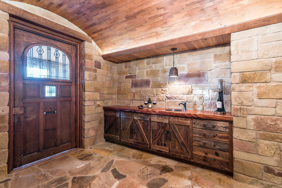 This is an example of a mid-sized mediterranean wine cellar in Austin with limestone floors and diamond bins.