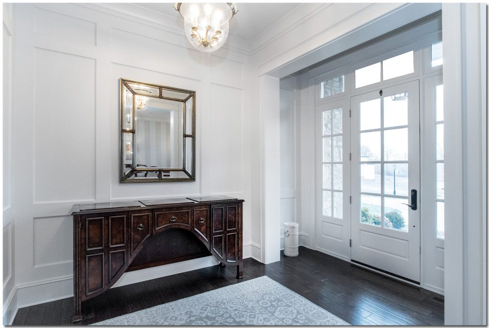 クリーブランドにあるラグジュアリーな広いトラディショナルスタイルのおしゃれな玄関ロビー (白い壁、濃色無垢フローリング、白いドア、茶色い床、羽目板の壁) の写真