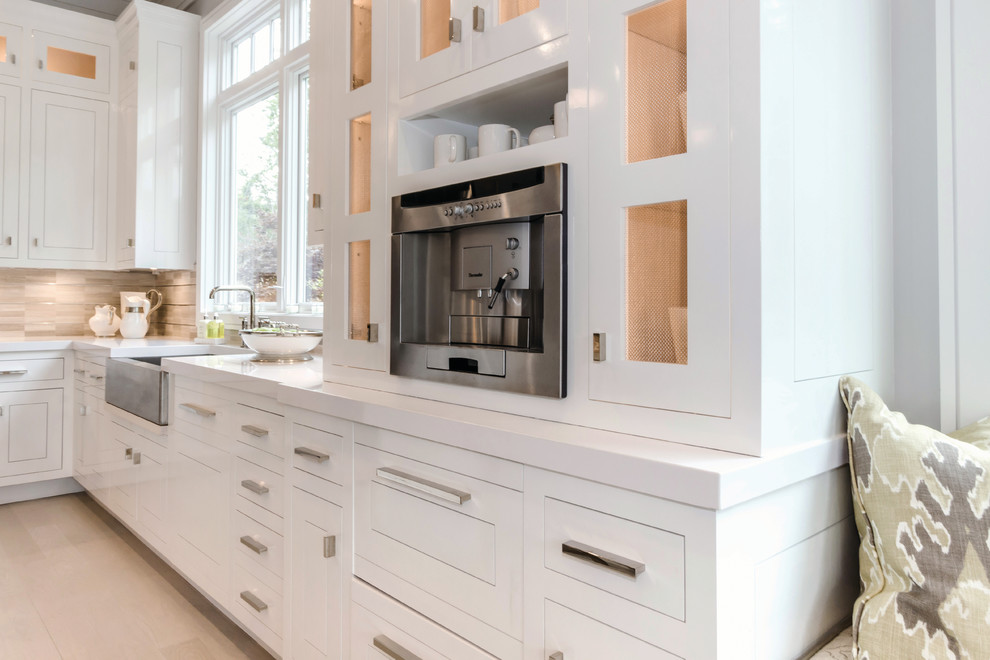 This is an example of a large beach style u-shaped eat-in kitchen in Other with a farmhouse sink, white cabinets, beige splashback, stainless steel appliances, light hardwood floors and with island.