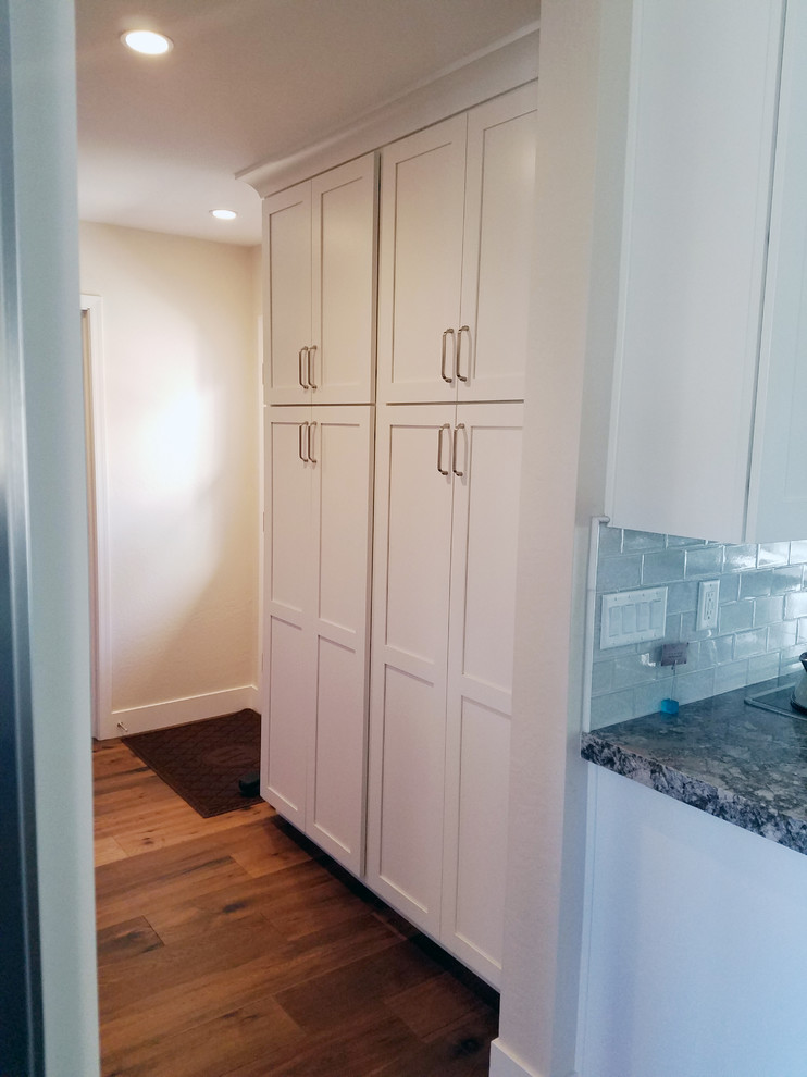 Eat-in kitchen - large transitional l-shaped medium tone wood floor eat-in kitchen idea in Phoenix with an undermount sink, shaker cabinets, white cabinets, granite countertops, gray backsplash, subway tile backsplash, stainless steel appliances and an island
