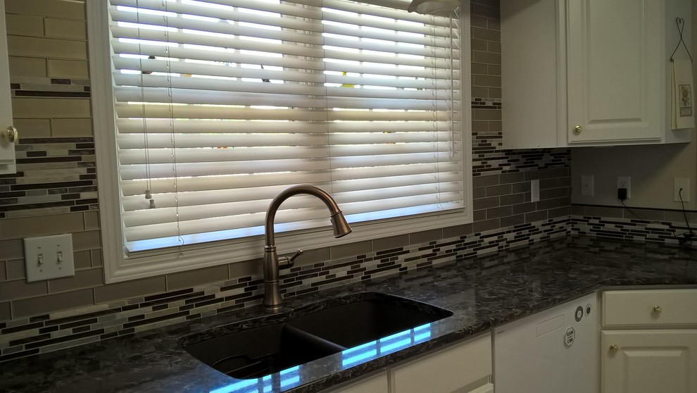 Example of a transitional kitchen design with a double-bowl sink, raised-panel cabinets, white cabinets, granite countertops, multicolored backsplash, glass tile backsplash and stainless steel appliances