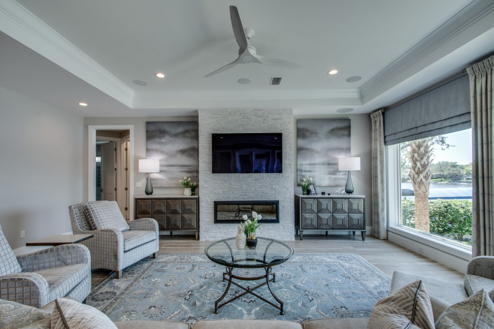 This is an example of a large transitional open concept living room in Other with grey walls, a stone fireplace surround, a wall-mounted tv and beige floor.