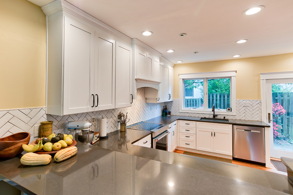 Photo of a mid-sized transitional u-shaped eat-in kitchen in Philadelphia with shaker cabinets, white cabinets, glass benchtops, white splashback, subway tile splashback, light hardwood floors, a peninsula, multi-coloured floor, brown benchtop, an undermount sink and stainless steel appliances.