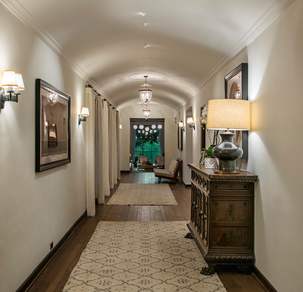 Mediterranean hallway in Santa Barbara with beige walls and dark hardwood floors.