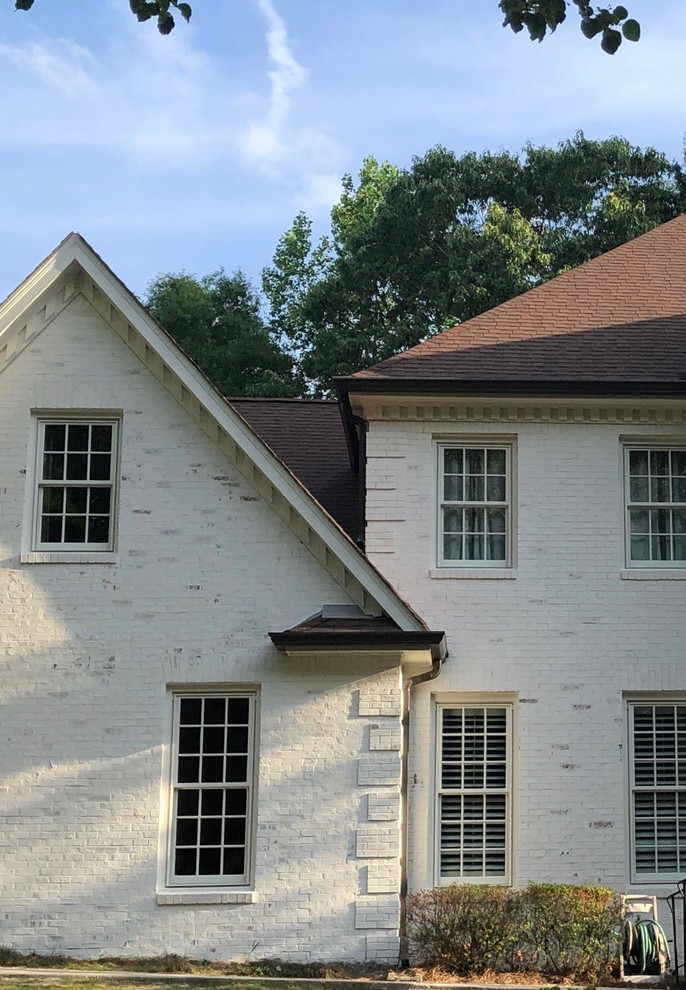 This is an example of a large traditional three-storey brick white house exterior in Atlanta with a gable roof and a shingle roof.