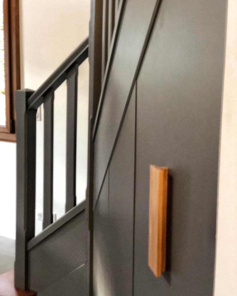 На фото: изогнутая деревянная лестница среднего размера в современном стиле с деревянными ступенями, деревянными перилами, деревянными стенами и кладовкой или шкафом под ней