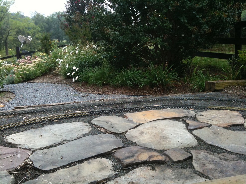 Inspiration for a large rustic partial sun backyard stone formal garden for summer.