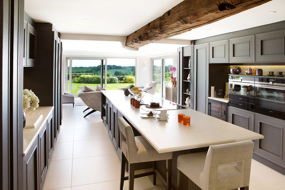 This is an example of a large traditional galley eat-in kitchen in West Midlands with shaker cabinets, dark wood cabinets, granite benchtops, black appliances, with island, ceramic floors and exposed beam.