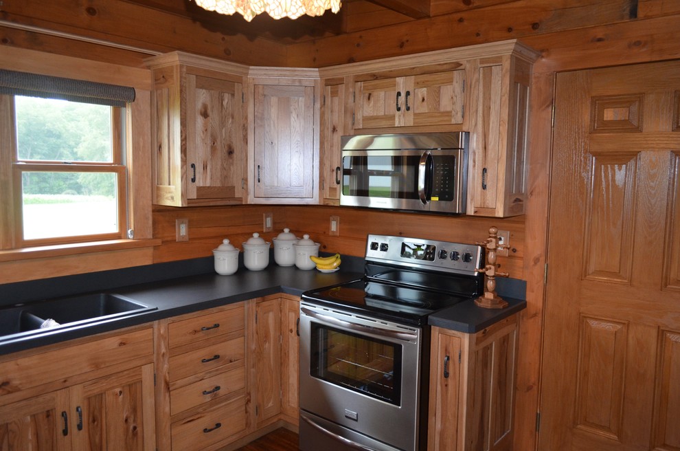 Mid-sized mountain style u-shaped dark wood floor and brown floor eat-in kitchen photo with a double-bowl sink, recessed-panel cabinets, medium tone wood cabinets, solid surface countertops, stainless steel appliances and a peninsula