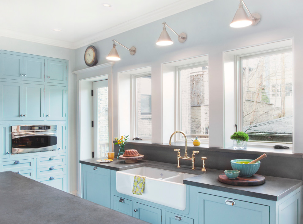Inspiration for a traditional u-shaped eat-in kitchen in Chicago with a farmhouse sink, blue cabinets, concrete benchtops and stainless steel appliances.