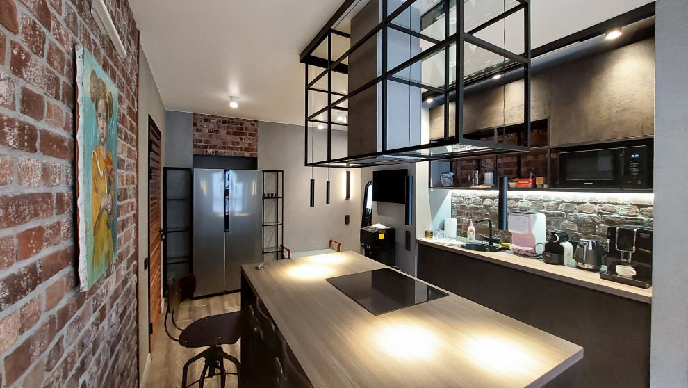 Large industrial galley eat-in kitchen in Moscow with an undermount sink, flat-panel cabinets, black cabinets, wood benchtops, brown splashback, brick splashback, stainless steel appliances, medium hardwood floors, with island, brown floor and brown benchtop.