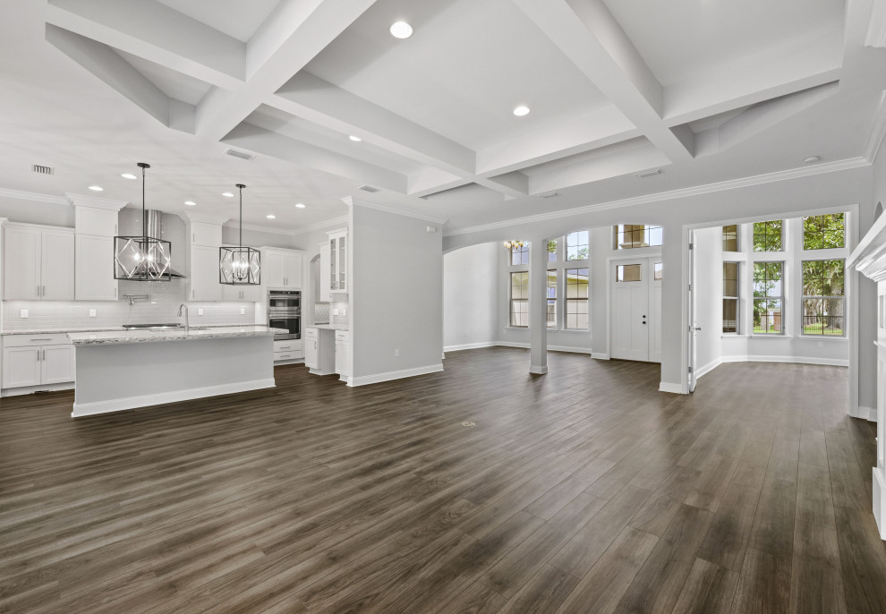 Inspiration for a large mediterranean open concept family room in Jacksonville with grey walls, vinyl floors, a standard fireplace, a wood fireplace surround, brown floor and coffered.