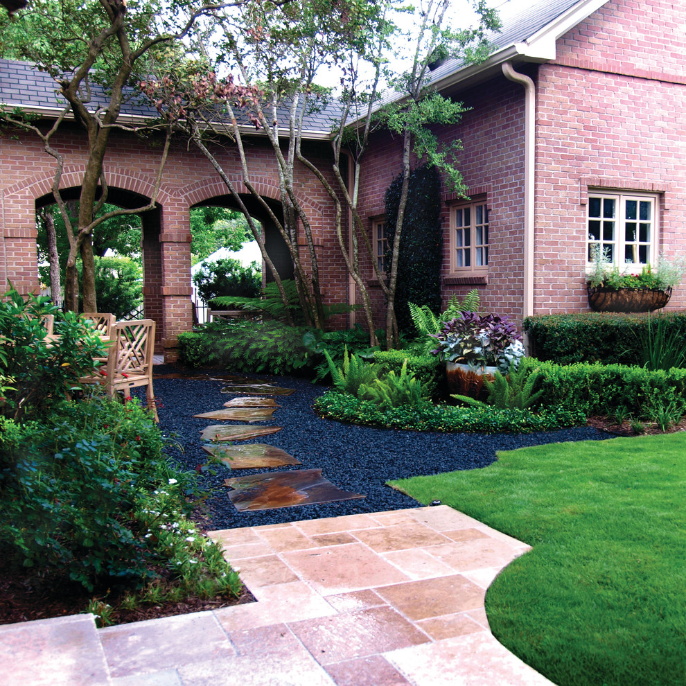 Photo of a large traditional backyard shaded garden in Houston with gravel.