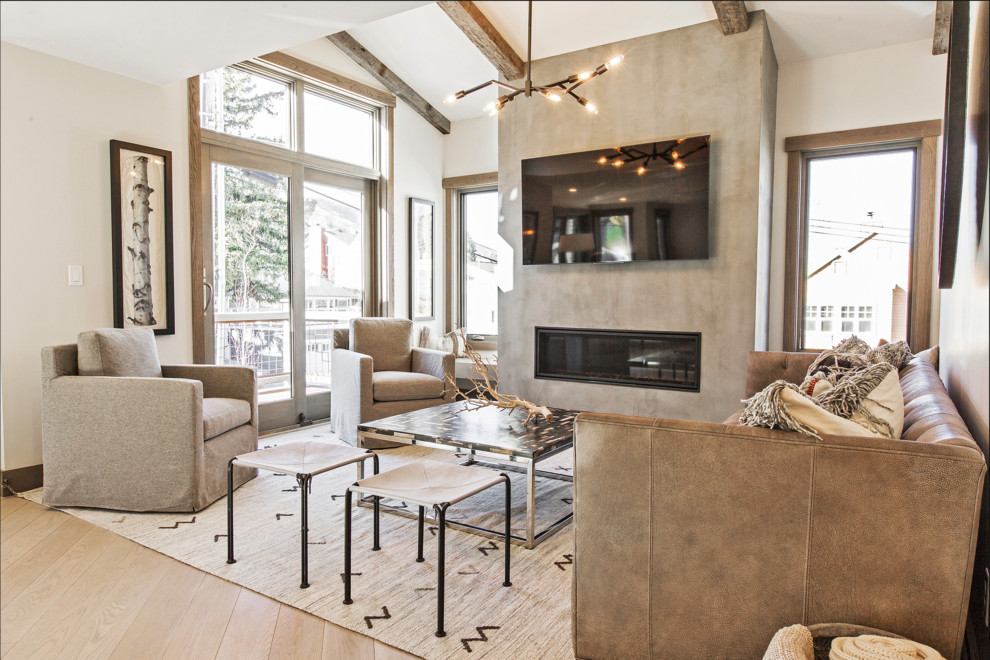 This is an example of a mid-sized contemporary open concept living room in Salt Lake City with white walls, light hardwood floors, a standard fireplace, a concrete fireplace surround and a wall-mounted tv.