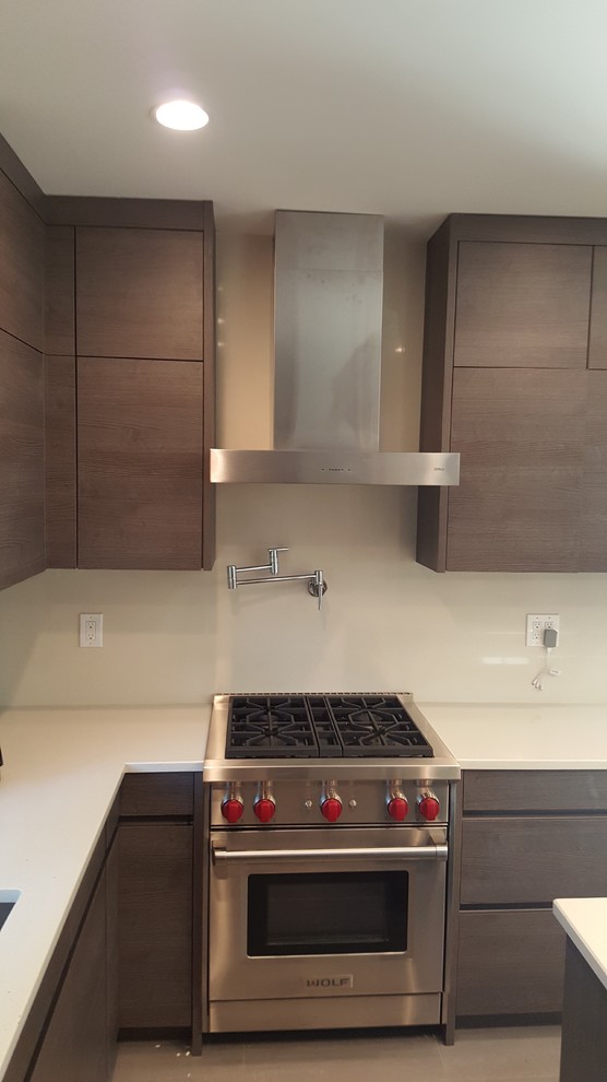 Photo of a mid-sized modern u-shaped kitchen pantry in New York with a single-bowl sink, flat-panel cabinets, brown cabinets, quartz benchtops, beige splashback, stone slab splashback, stainless steel appliances, ceramic floors and with island.