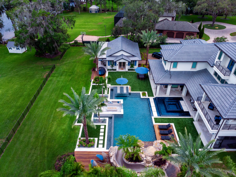 This is an example of a large contemporary backyard custom-shaped infinity pool in Tampa with with a pool and tile.