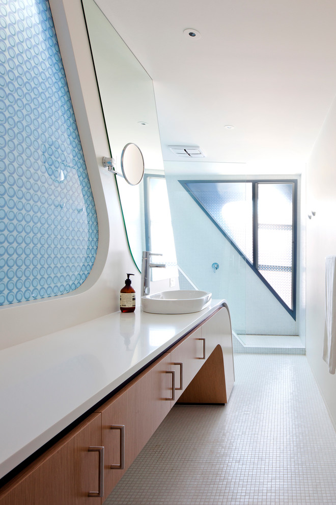This is an example of a large contemporary master bathroom in Melbourne with a vessel sink, flat-panel cabinets, solid surface benchtops, an open shower, white tile, ceramic tile, white walls, mosaic tile floors, medium wood cabinets and an open shower.