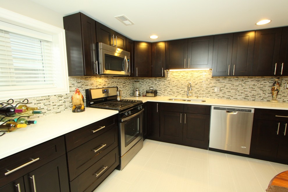 Inspiration for a small transitional l-shaped porcelain tile and gray floor kitchen remodel in Chicago with an undermount sink, recessed-panel cabinets, black cabinets, quartz countertops, multicolored backsplash, matchstick tile backsplash, stainless steel appliances, no island and white countertops