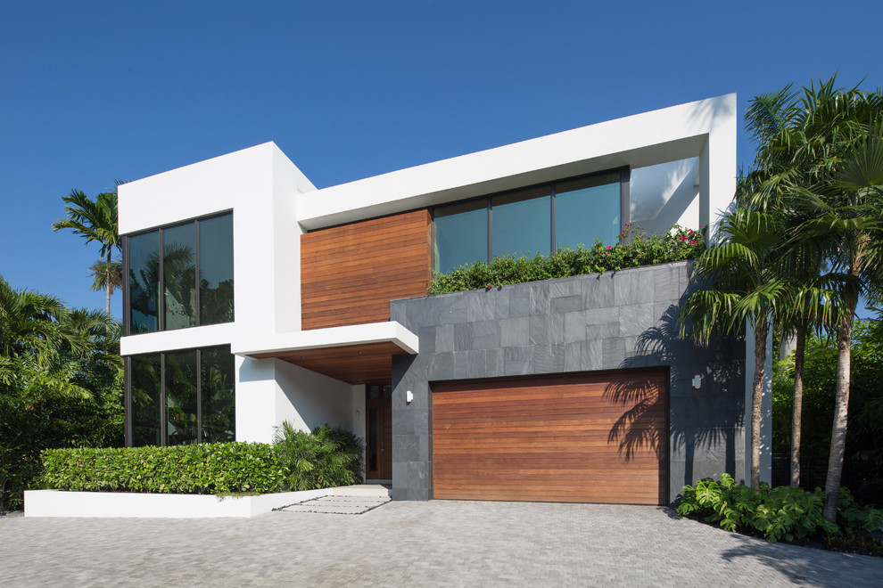 Inspiration for a large contemporary two-storey white house exterior in Miami with wood siding and a flat roof.