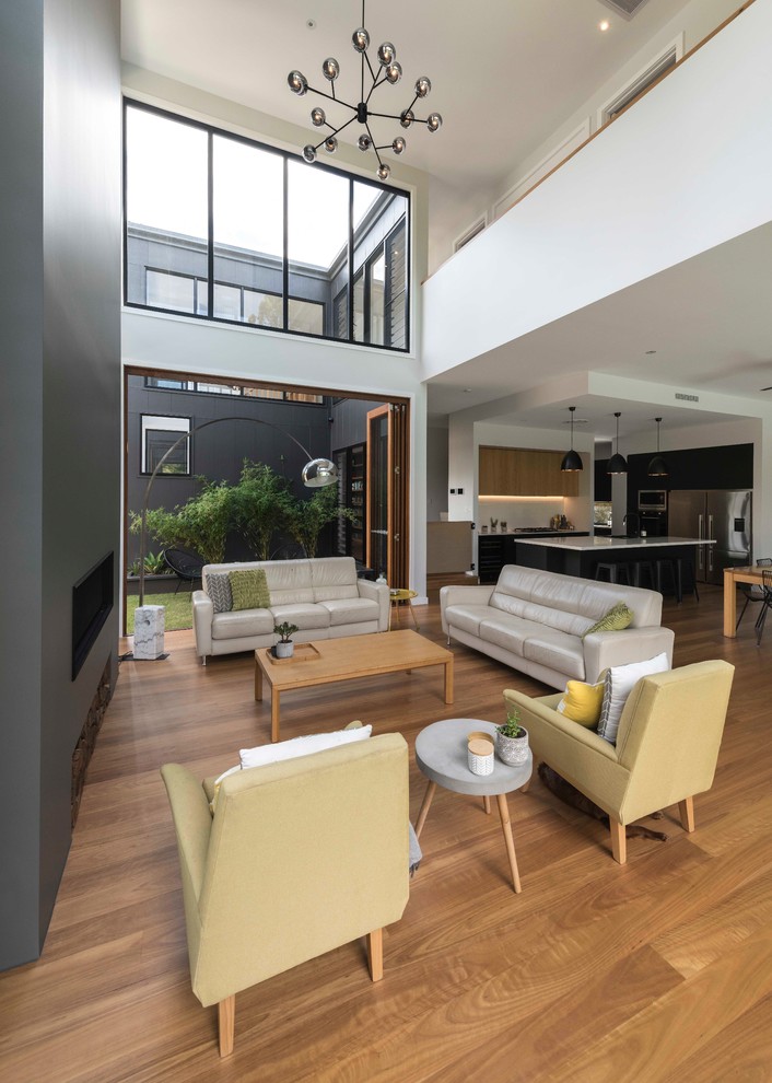 Photo of a contemporary open concept living room in Brisbane with white walls, medium hardwood floors and brown floor.