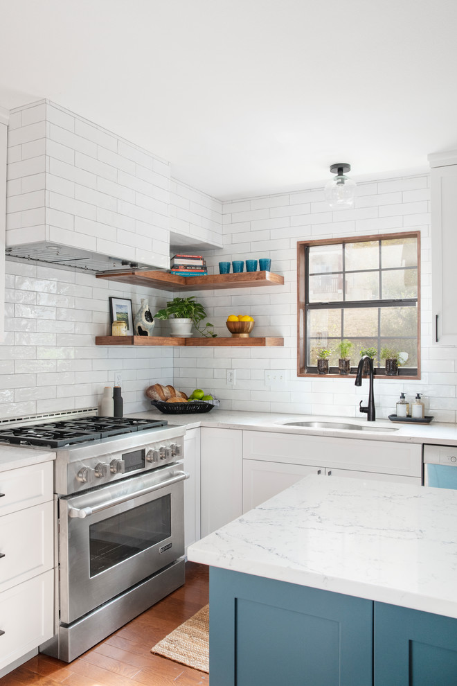 Example of a transitional l-shaped dark wood floor eat-in kitchen design in Austin with an undermount sink, shaker cabinets, quartz countertops, stainless steel appliances, an island, white cabinets, white backsplash, subway tile backsplash and white countertops