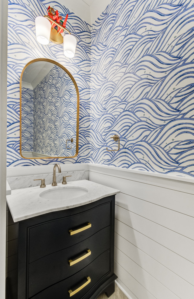 Inspiration for a small beach style cloakroom in Charleston with beaded cabinets, blue cabinets, blue walls, medium hardwood flooring, a submerged sink, marble worktops, brown floors, grey worktops, a freestanding vanity unit and wallpapered walls.
