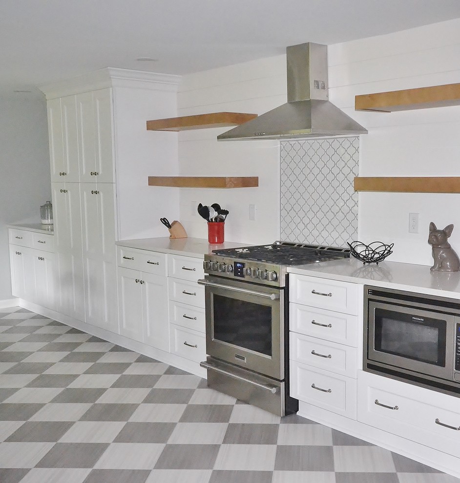 This is an example of a large transitional u-shaped eat-in kitchen in Philadelphia with an undermount sink, raised-panel cabinets, white cabinets, quartz benchtops, white splashback, timber splashback, stainless steel appliances, ceramic floors, no island, multi-coloured floor and white benchtop.