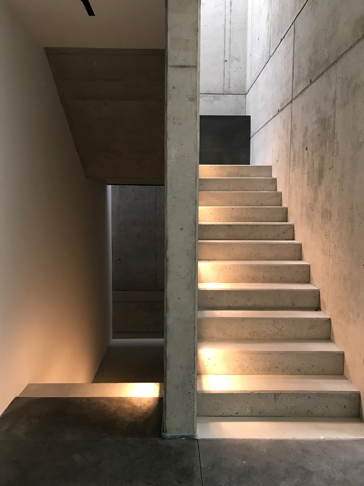 Photo of a mid-sized modern concrete u-shaped staircase in Other with concrete risers.