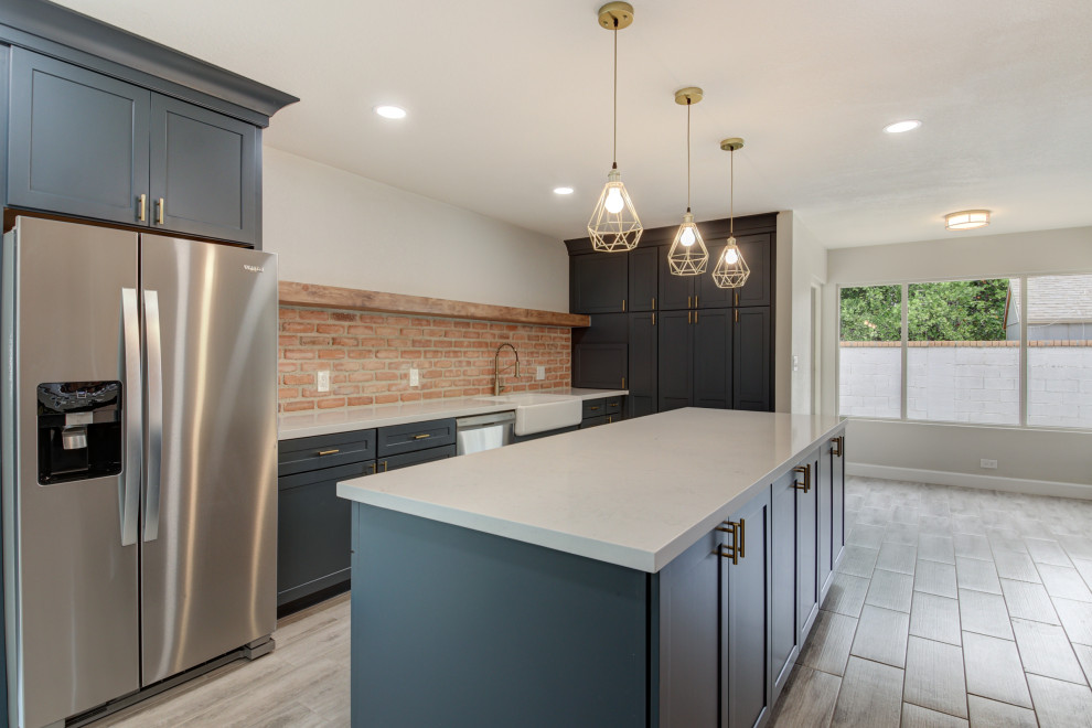 Inspiration for a mid-sized transitional u-shaped porcelain tile and gray floor eat-in kitchen remodel in Phoenix with a farmhouse sink, shaker cabinets, blue cabinets, quartz countertops, red backsplash, brick backsplash, stainless steel appliances, an island and white countertops