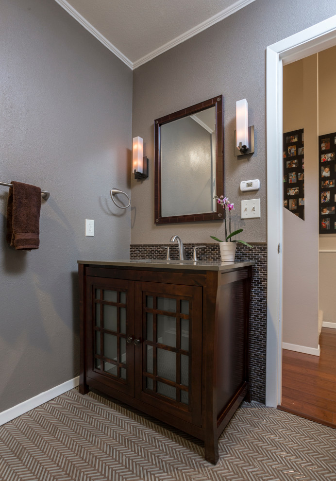 Photo of a small asian 3/4 bathroom in Portland with furniture-like cabinets, dark wood cabinets, a corner shower, a one-piece toilet, multi-coloured tile, glass tile, grey walls, porcelain floors, an integrated sink, engineered quartz benchtops, multi-coloured floor, a hinged shower door and grey benchtops.