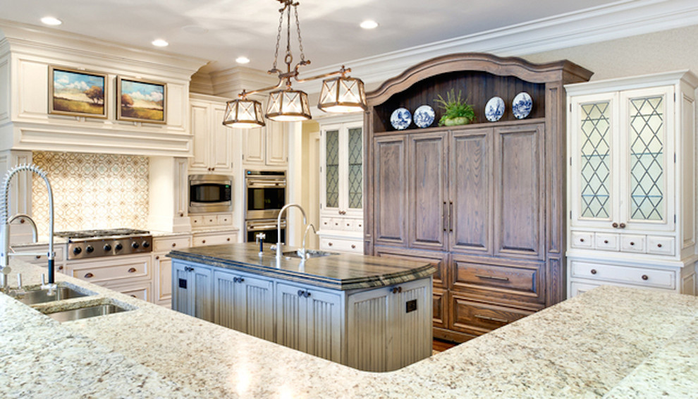 Example of a mid-sized transitional u-shaped travertine floor and beige floor open concept kitchen design with an undermount sink, shaker cabinets, white cabinets, marble countertops, beige backsplash, ceramic backsplash, stainless steel appliances and an island