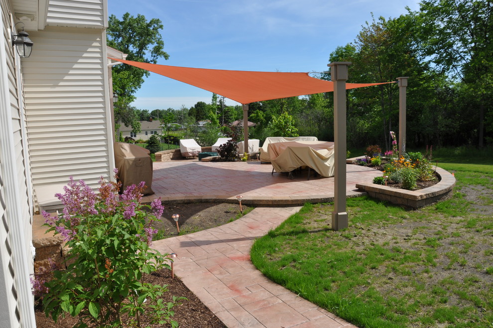 Large traditional backyard patio in Cleveland with brick pavers and an awning.