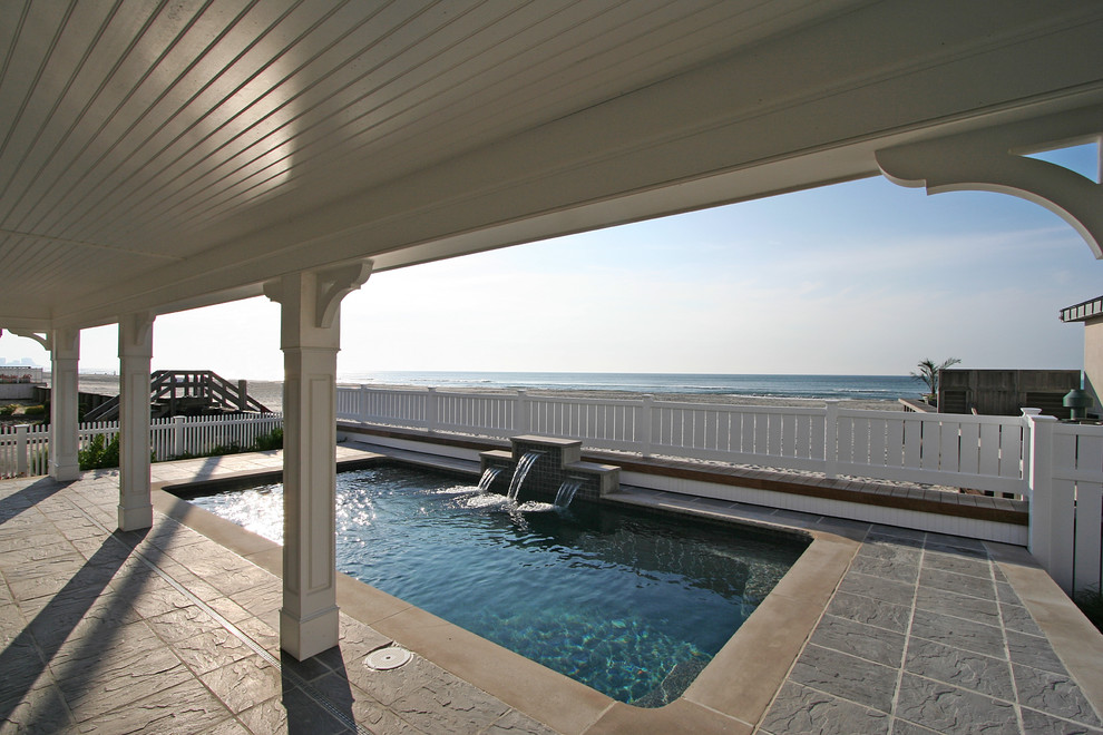 Design ideas for a large beach style backyard rectangular natural pool in Philadelphia with natural stone pavers.