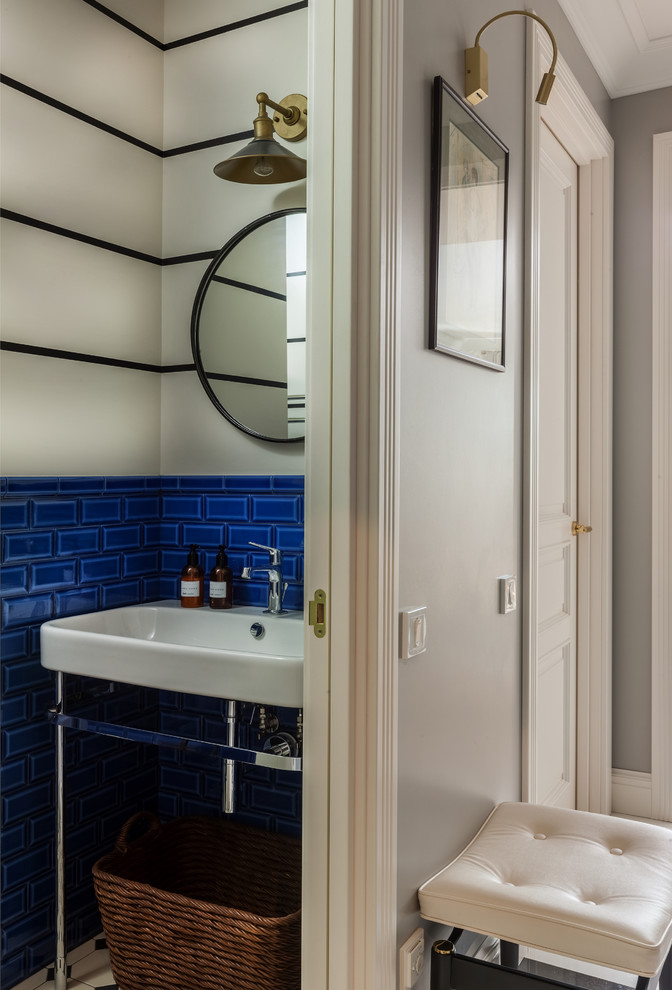 Photo of a transitional powder room with blue tile, subway tile, white walls and a console sink.