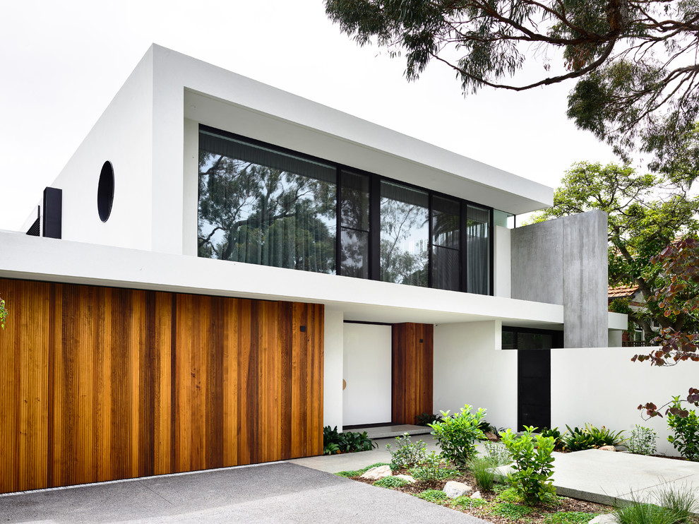 Photo of a contemporary two-storey stucco white house exterior in Melbourne with a flat roof.