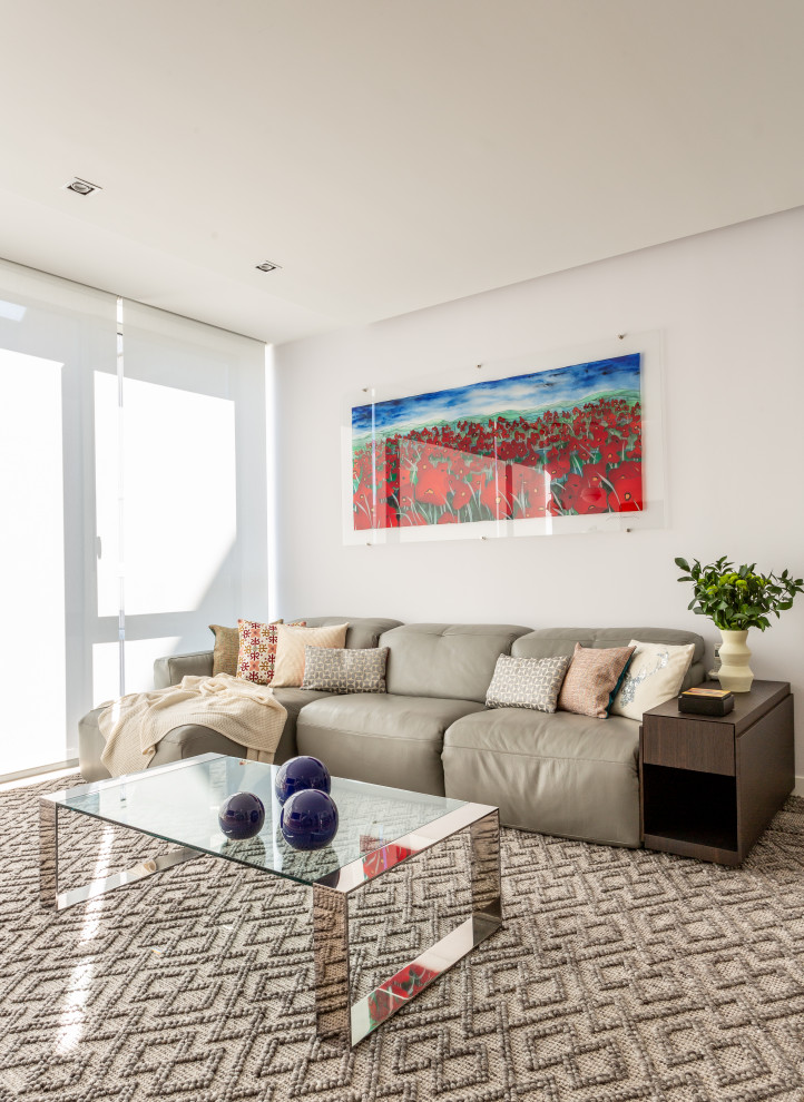 This is an example of a large contemporary enclosed living room in Madrid with white walls, light hardwood floors and a wall-mounted tv.