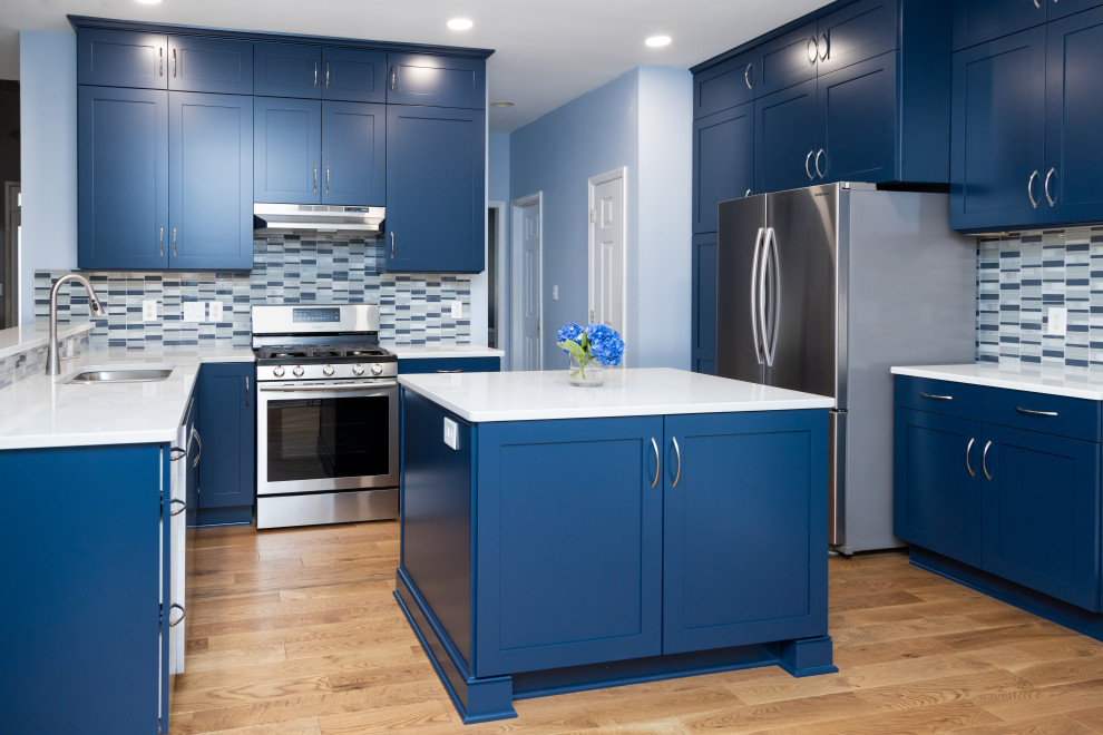 Foto de cocina contemporánea grande con armarios estilo shaker, puertas de armario azules, encimera de cuarzo compacto, salpicadero de azulejos de vidrio, una isla y encimeras blancas