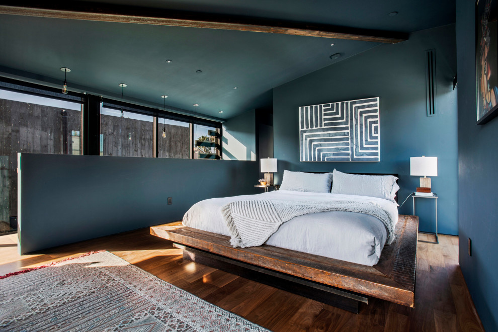 Immagine di una camera degli ospiti industriale di medie dimensioni con pareti blu, nessun camino, pavimento in legno massello medio, pavimento marrone e travi a vista
