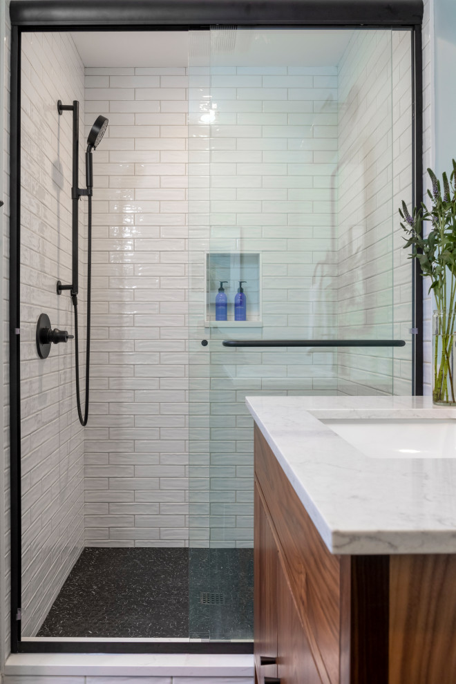 Cette image montre une petite salle de bain minimaliste en bois brun avec un placard à porte plane, un carrelage blanc, un carrelage métro, un lavabo encastré, un sol noir, une cabine de douche à porte coulissante, une niche, meuble simple vasque et meuble-lavabo sur pied.