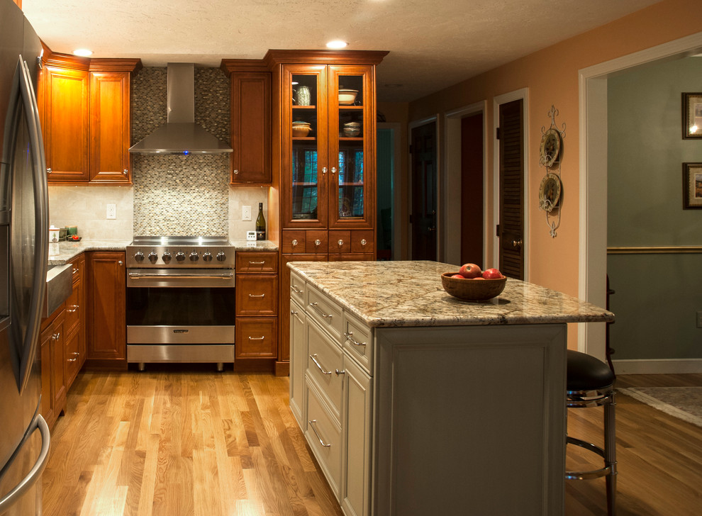 Inspiration for a mid-sized transitional l-shaped medium tone wood floor eat-in kitchen remodel in Boston with a farmhouse sink, flat-panel cabinets, medium tone wood cabinets, granite countertops, beige backsplash, subway tile backsplash, stainless steel appliances and an island