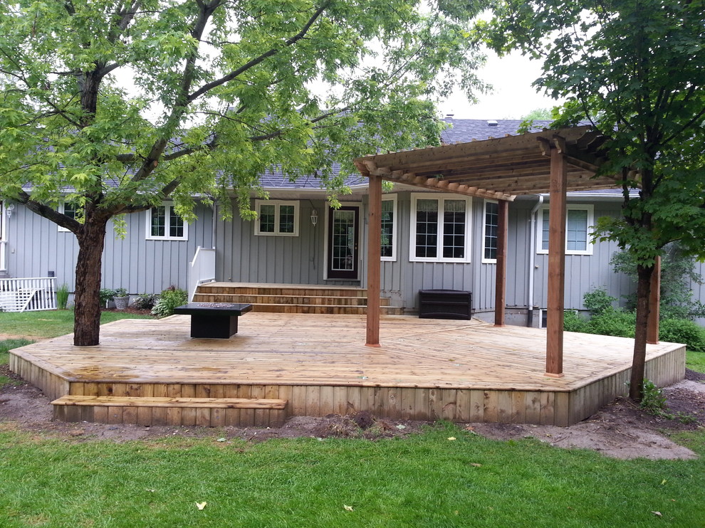 This is an example of a mid-sized country backyard deck in Toronto with a pergola.