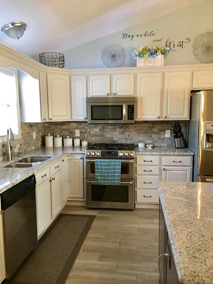 Eat-in kitchen - mid-sized l-shaped eat-in kitchen idea with an undermount sink, raised-panel cabinets, dark wood cabinets, granite countertops, multicolored backsplash, subway tile backsplash, stainless steel appliances and an island