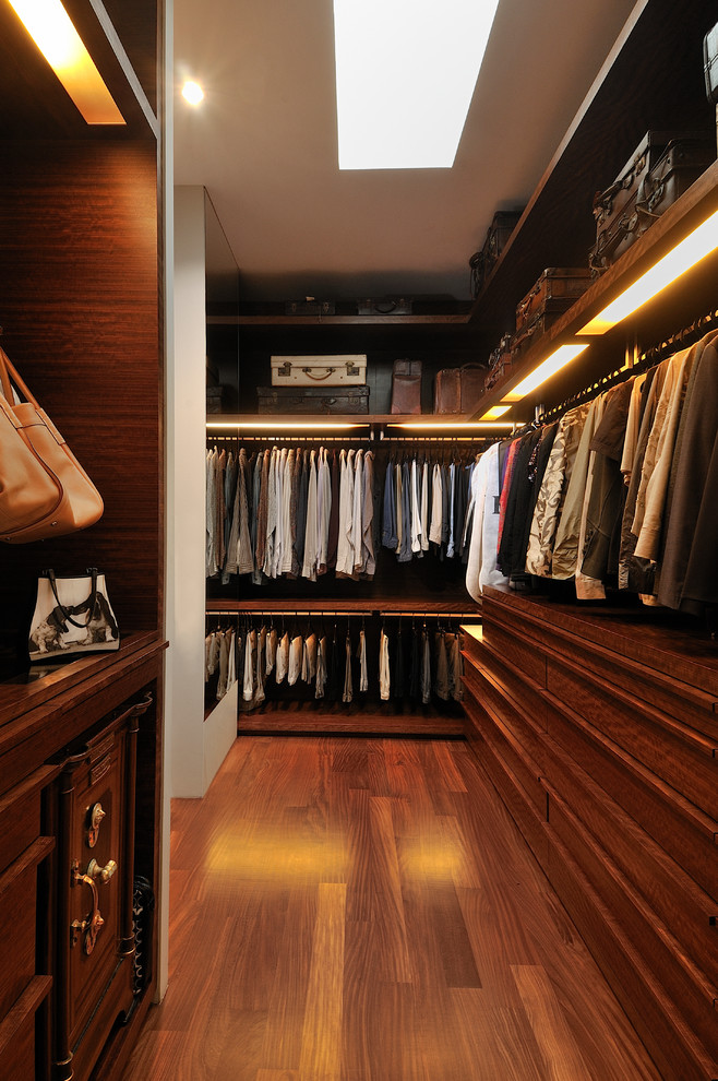 This is an example of a contemporary gender-neutral walk-in wardrobe in Singapore with dark wood cabinets and brown floor.
