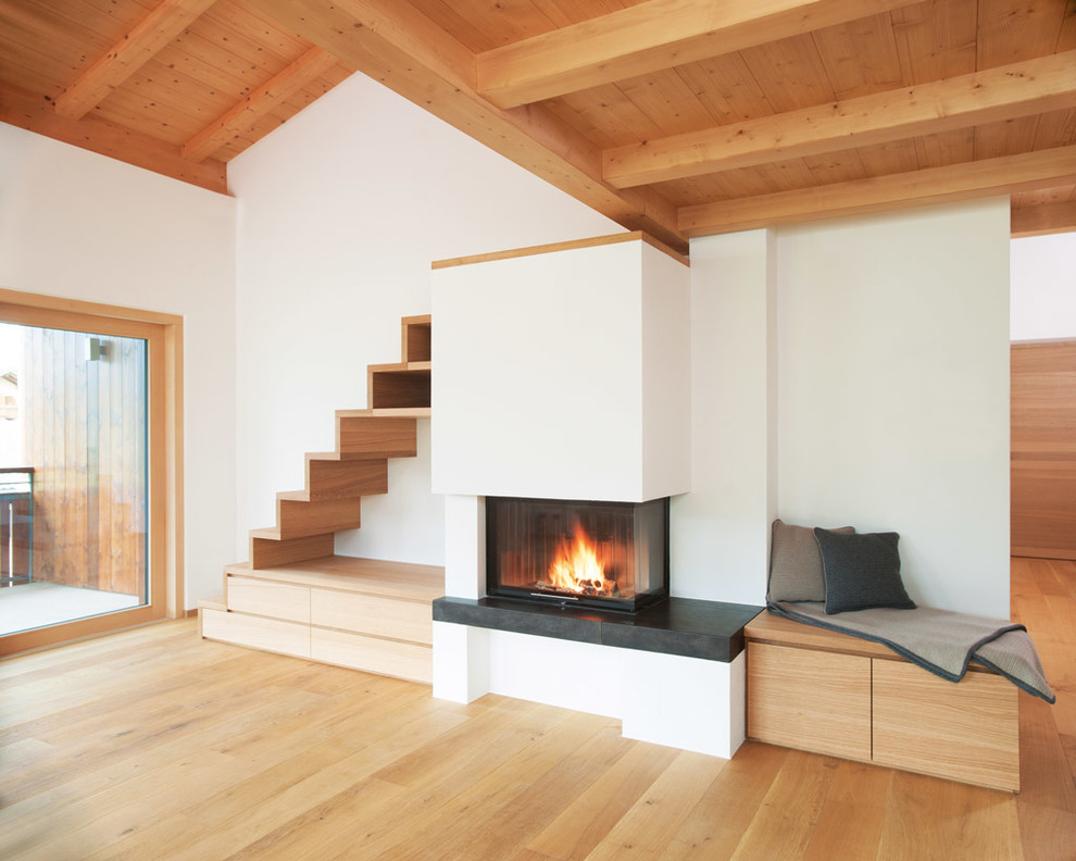 Inspiration for a country living room in Bremen with a standard fireplace, white walls and light hardwood floors.