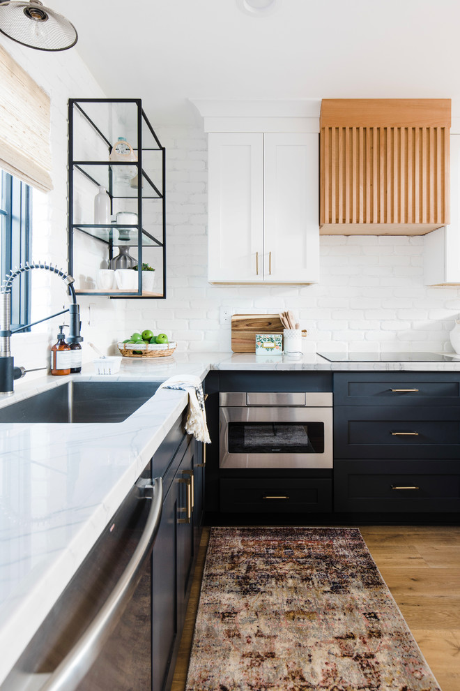 Inspiration for a mid-sized modern l-shaped eat-in kitchen in Phoenix with an undermount sink, shaker cabinets, blue cabinets, quartzite benchtops, white splashback, brick splashback, stainless steel appliances, light hardwood floors, beige floor and white benchtop.
