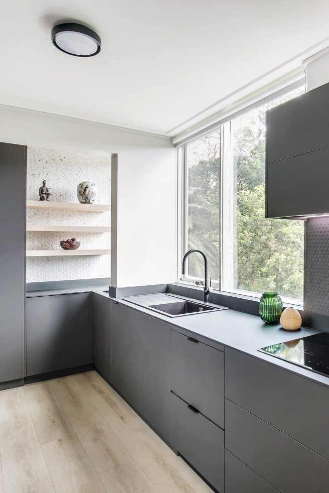 Mid-sized contemporary u-shaped eat-in kitchen in Sydney with a single-bowl sink, flat-panel cabinets, brown cabinets, tile benchtops, brown splashback, ceramic splashback, stainless steel appliances, light hardwood floors, no island, brown floor, black benchtop and exposed beam.