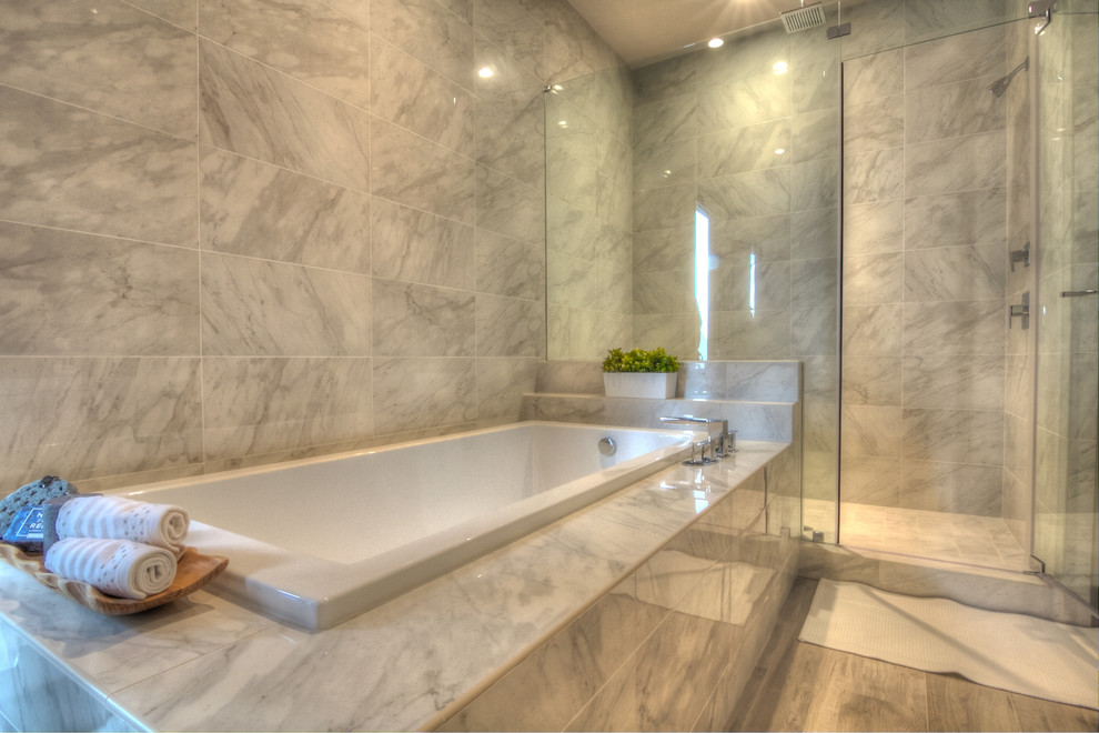 Large contemporary master bathroom in Houston with flat-panel cabinets, white cabinets, a corner tub, an alcove shower, a one-piece toilet, gray tile, marble, grey walls, laminate floors, an undermount sink, solid surface benchtops, grey floor and a hinged shower door.