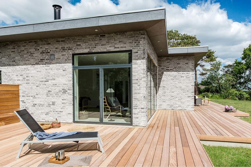 This is an example of a mid-sized contemporary backyard deck in Aarhus with no cover.