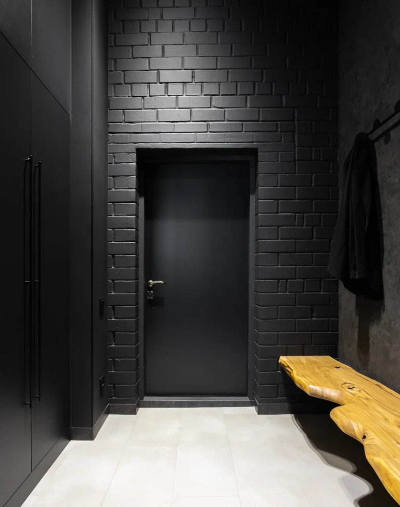 Industriell inredning av en hall, med svarta väggar, en enkeldörr, en svart dörr och grått golv
