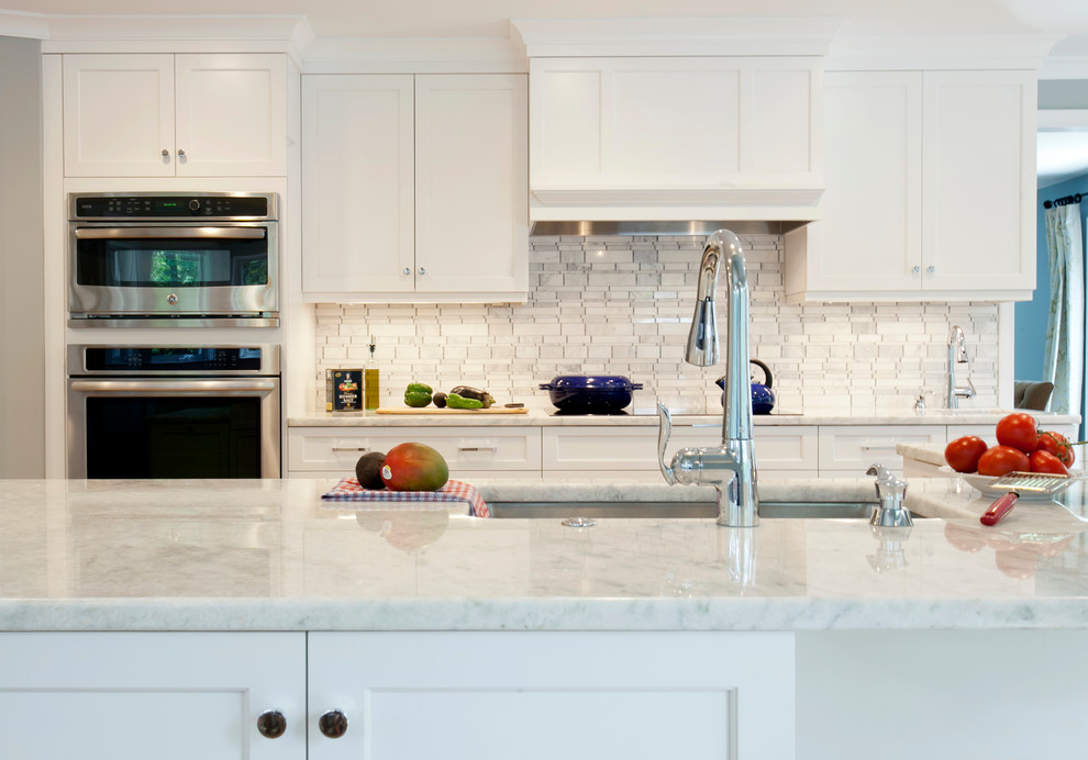 Inspiration for a large transitional l-shaped eat-in kitchen in Bridgeport with an undermount sink, recessed-panel cabinets, white cabinets, quartzite benchtops, grey splashback, stone tile splashback, stainless steel appliances, light hardwood floors and with island.